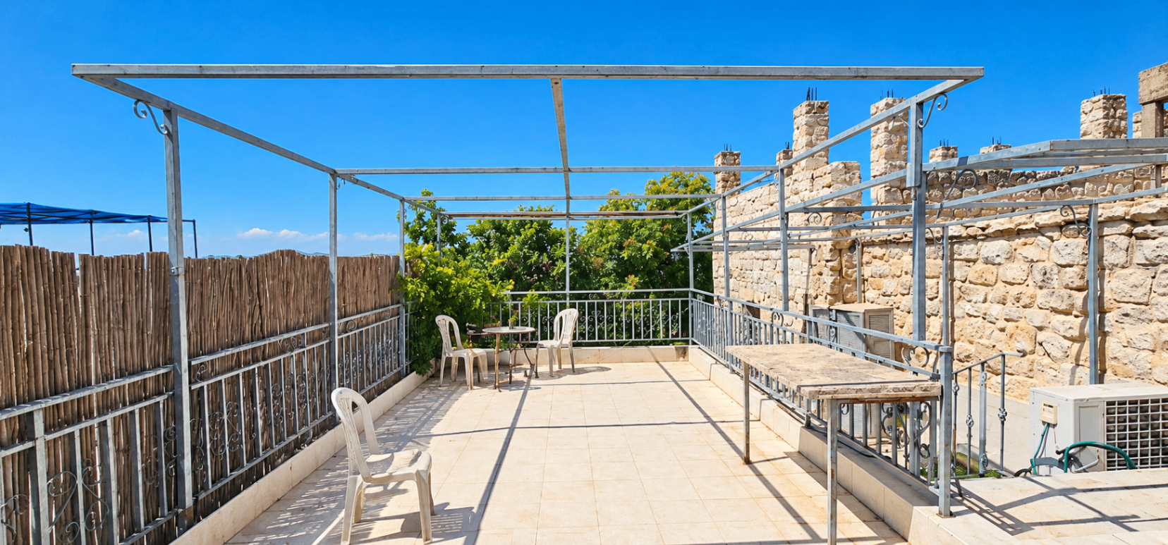 גג מרפסת רחב עם קירות אבן, פינת ישיבה ושמיים כחולים