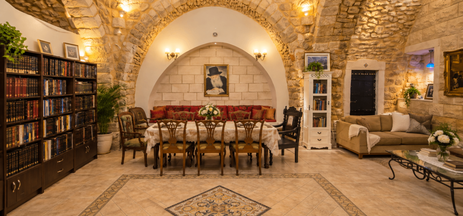 פינת אוכל ארוכה לצד ספרייה וספסל כריות אדומות בחלל אבן קמור
