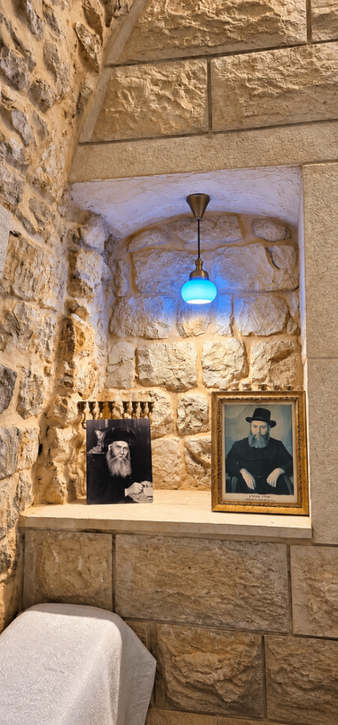 גומחת אבן עם תמונות ישנות, מנורת תאורה כחולה וכסא קטן